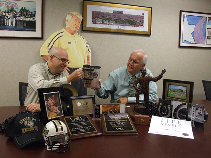 Dan Ward, '92 (left), and Roger Pynn, '73, toast their alma mater in the conference room at Curley & Pynn.