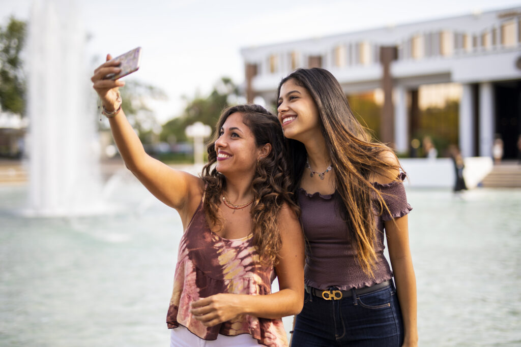 UCF Knightfluencers image - two girls by the UCF Reflecting Pond shooting a selfie