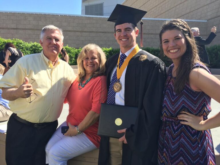 man in ucf regalia with family