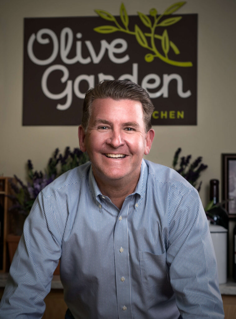 man in front of Olive Garden sign