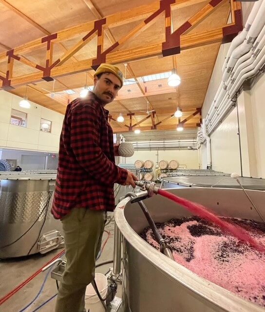 man stirring vat of wine