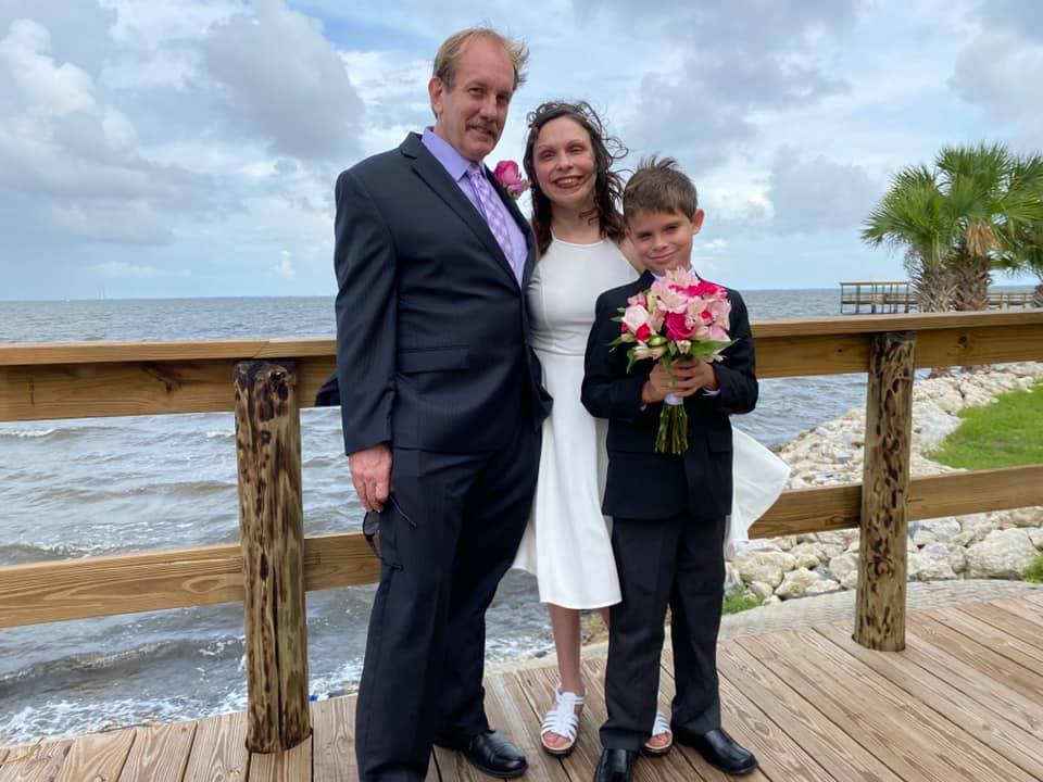 man, woman and child on a bridge in wedding attire