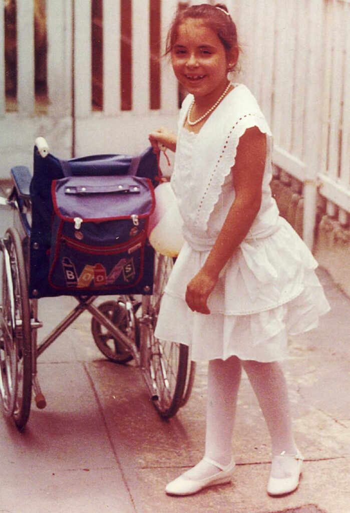 young girl standing in front of a wheelchair