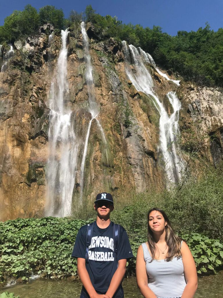 young man and woman in front of a waterfall