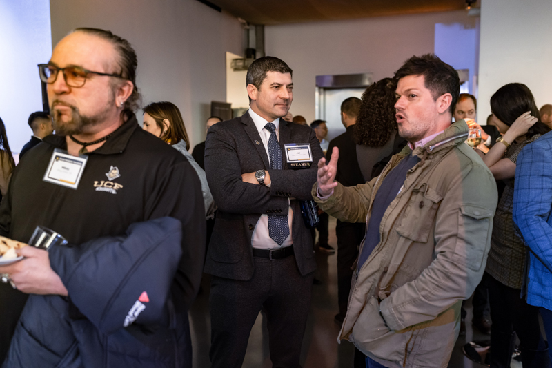 Group of professionals at a networking event conversing in a modern venue.
