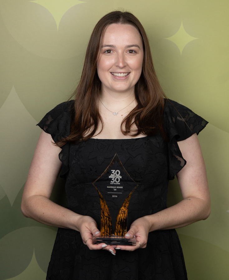 Young woman in a black dress holds a glass award with orange accents and the inscription 30/30, Hannah Miner, 2026.