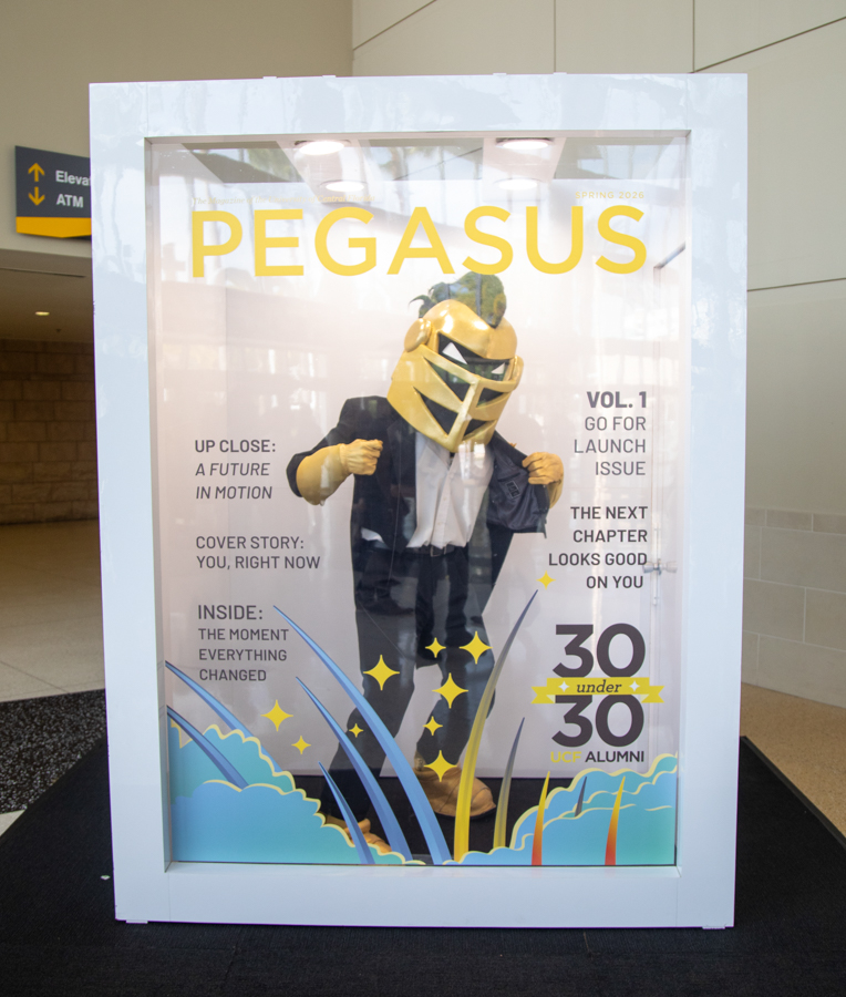Poster in a white frame featuring a person in a gold helmet and suit under a large PEGASUS title, celebrating 30 under 30 UCF Alumni.