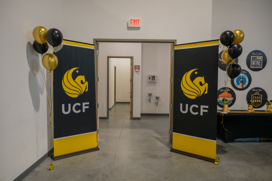 UCF-branded entry area with tall black and yellow banners, balloons, and double doors opening to a hallway.