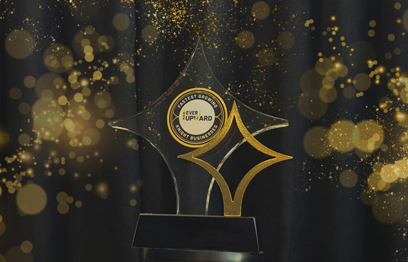 Crystal trophy with gold star shapes and a circular 'Fastest Growing Ever Upward' badge on a dark glittery backdrop.