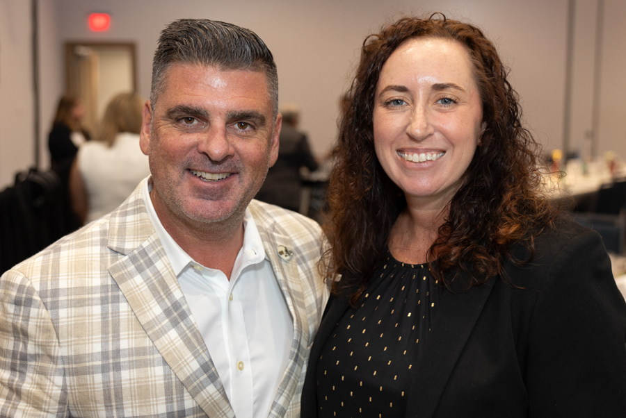 Two smiling professionals posing for a photo at a conference or networking event, standing close together in business attire.