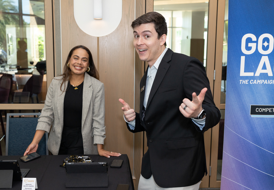 Two event staff at a registration table, smiling at the camera; a Go LA banner stands to the right.