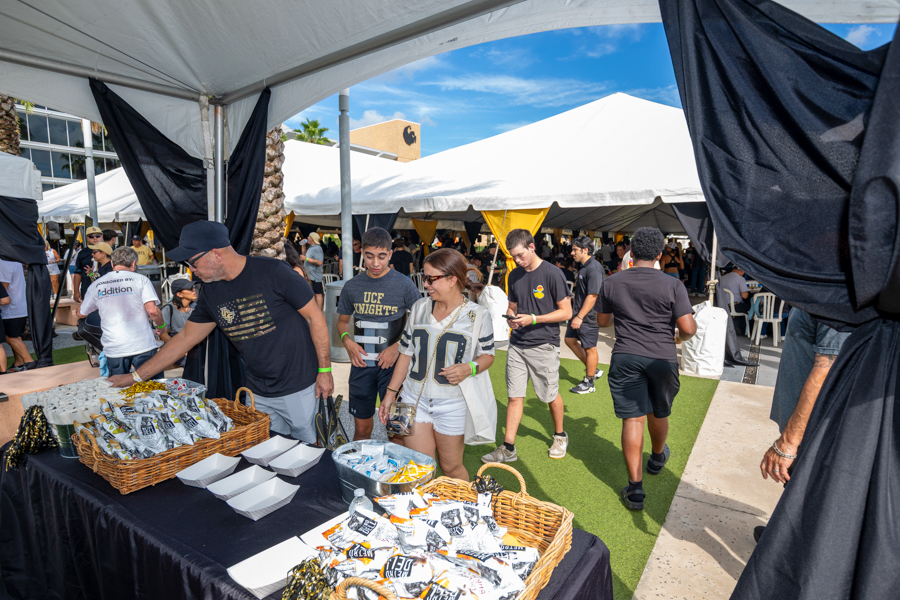 People browse a snack table under white tents at an outdoor festival or fair.