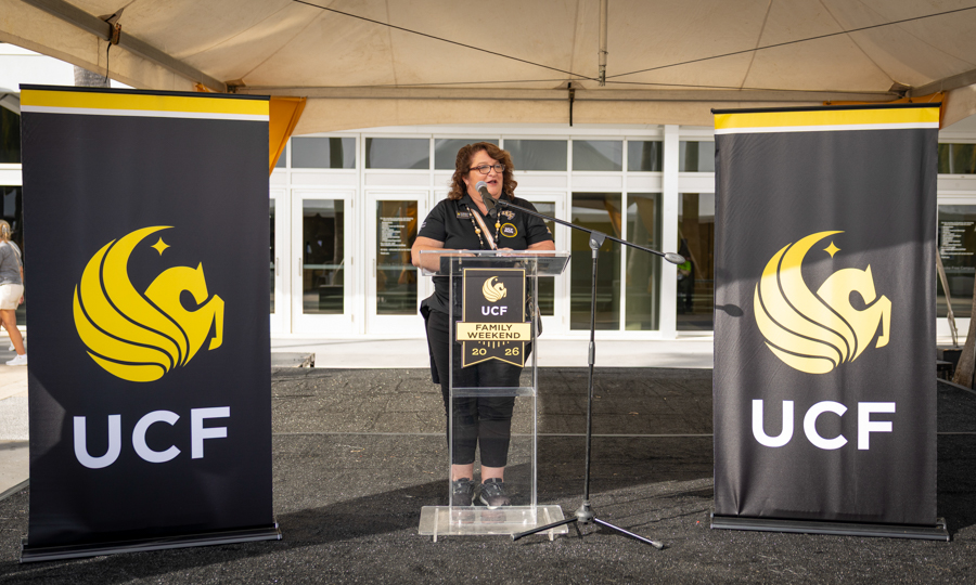 Speaker at a clear podium with a UCF banner on each side during a university event, year 2016 listed on the podium badge.