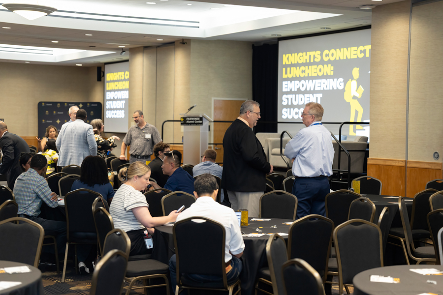 Networking luncheon in a conference room with attendees at round tables; banner reads 'Knights Connect Luncheon: Empowering Student Success'