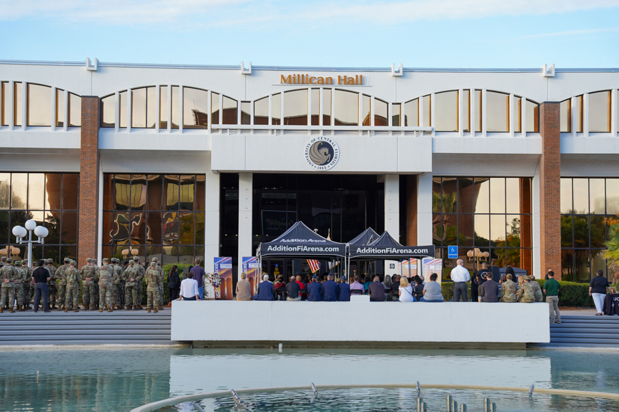 Front view of Millican Hall with a crowd gathered on the steps for an event, black tents with AddictionFIarena.com in front of the glass doors.
