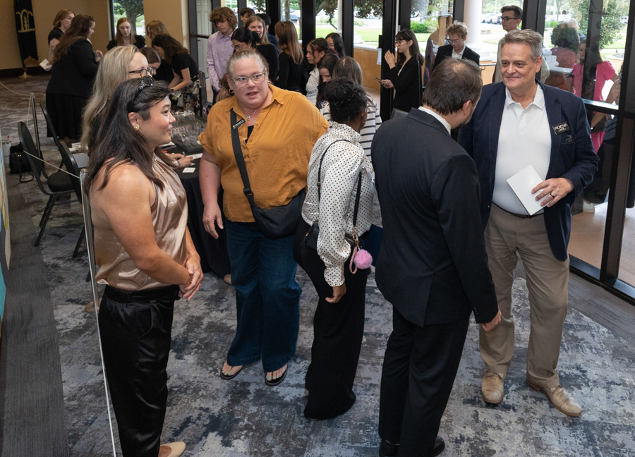 Professionals mingling at a networking event in a modern lobby, chatting near glass doors.