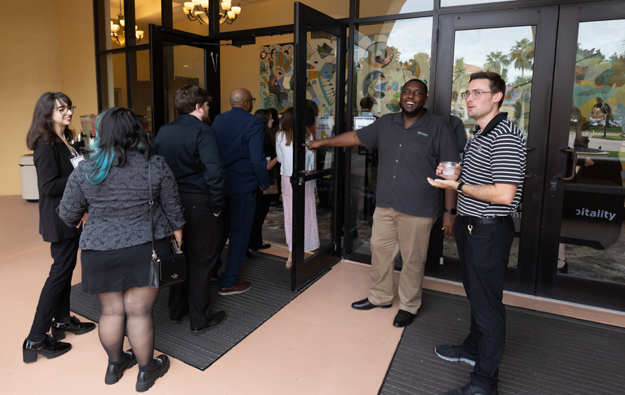 Group of people waiting to enter a building through glass doors at a social event outside.