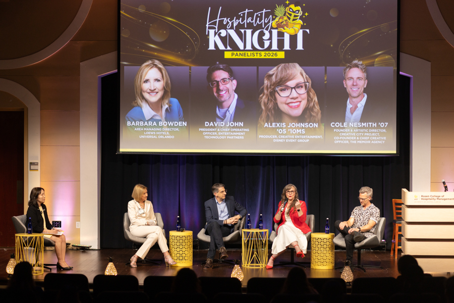 Five panelists sit in chairs on a stage for a panel discussion, with a large screen above showing 'Hospitality Knight' and the panelists' names and photos.