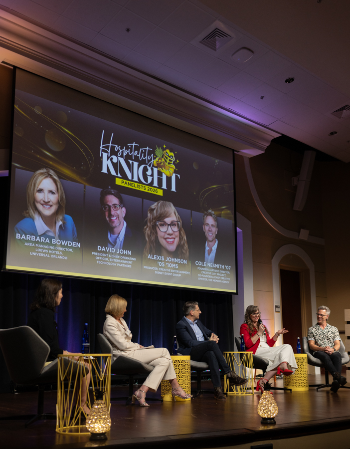 Five panelists seated on a stage during a conference panel, with a large screen behind them displaying 'Hospitality Knight' panelists 2026.