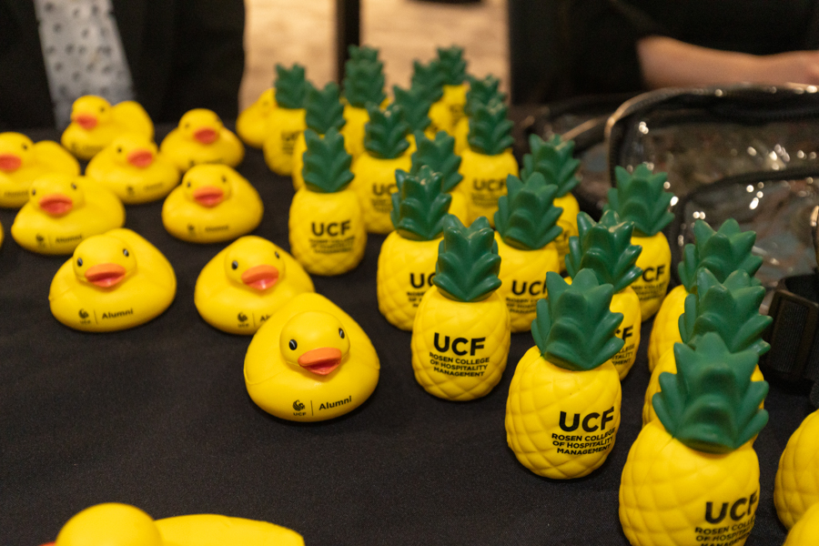 Row of yellow rubber ducks and pineapple-shaped UCF promotional items arranged on a black table.