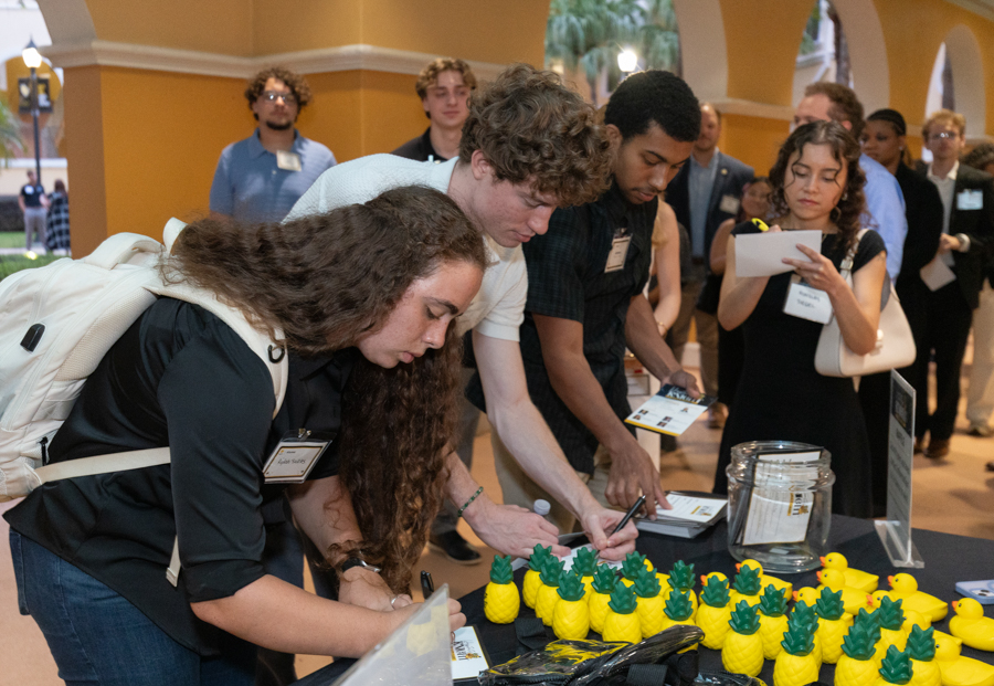 Group of people at a registration table, signing forms among yellow duck-shaped decorations at an event.