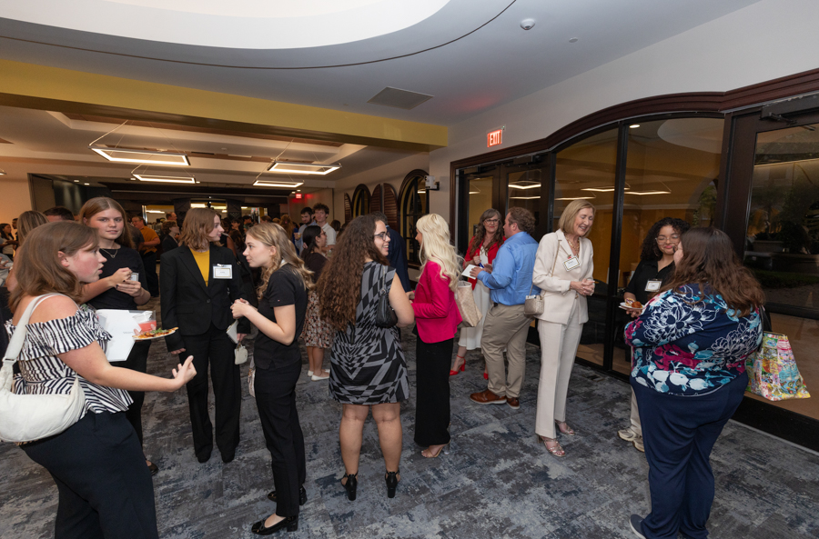 Group of professionals mingling at a corporate networking event in a bright lobby after a conference meal.Maybe too long?