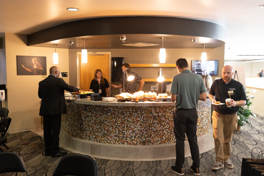 Curved mosaic-tile buffet counter with pastries and staff serving in a lounge area under warm pendant lights.
