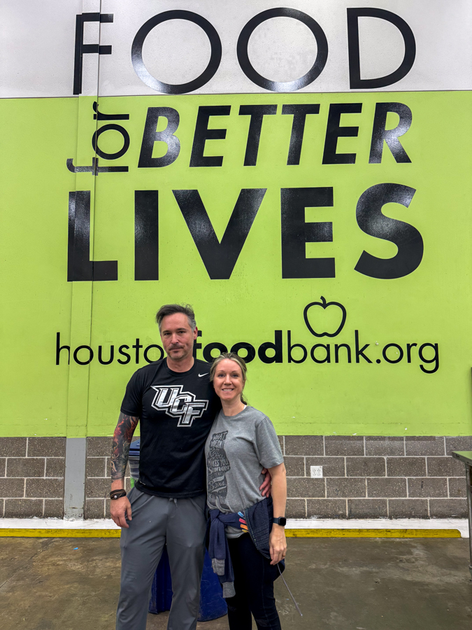 Man and woman stand in front of a lime banner that reads 'Food for Better Lives' with the Houston Food Bank logo.