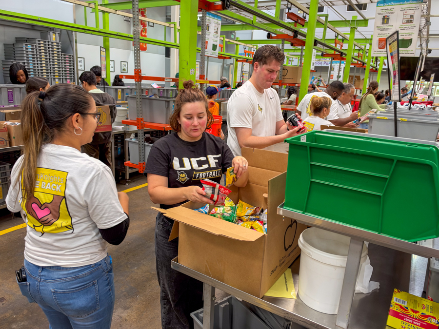 Volunteers in a warehouse sorting and packing snack bags at a distribution center.