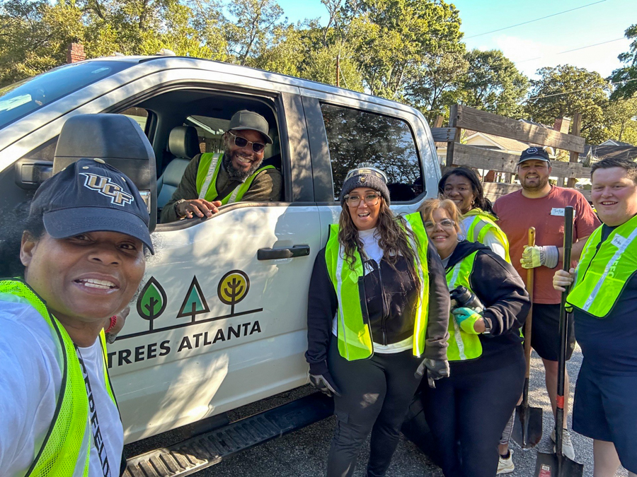 Group of volunteers in neon vests posing by a Trees Atlanta pickup truck with shovels in hand.