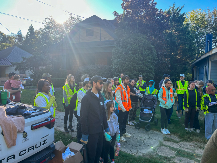 Group of volunteers in high-visibility vests gathered outside a residential street for a community service event.
